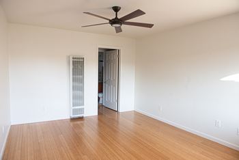 A room with a ceiling fan and a door leading to another room.